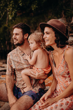 Family photo of three as they look away while seated
