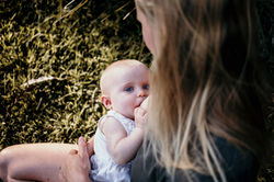 Baby girl breastfeeding in nature during sunset