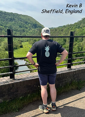 Photo of a man wearing the Islands To Highlands Recycled-Pineapple-Tee and Sandy Shoals Cap on a bridge in Sheffield England with a green valley in the background.