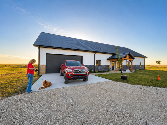 White barndominium shop with black metal roof and oversized garage doors