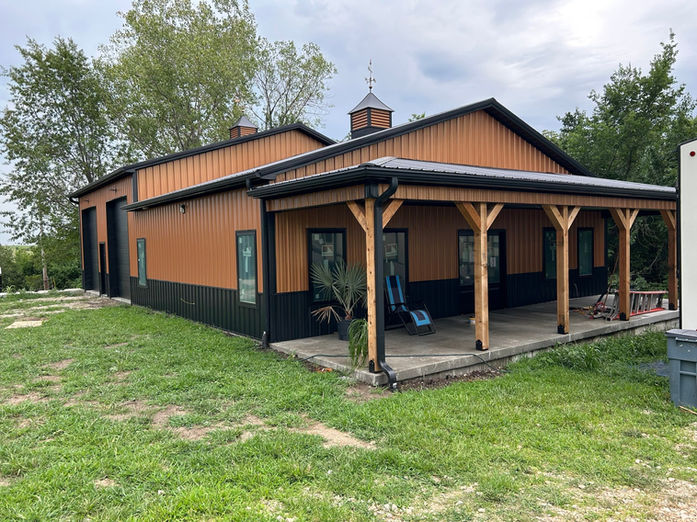 Custom copper barndominium with black trim and covered front porch