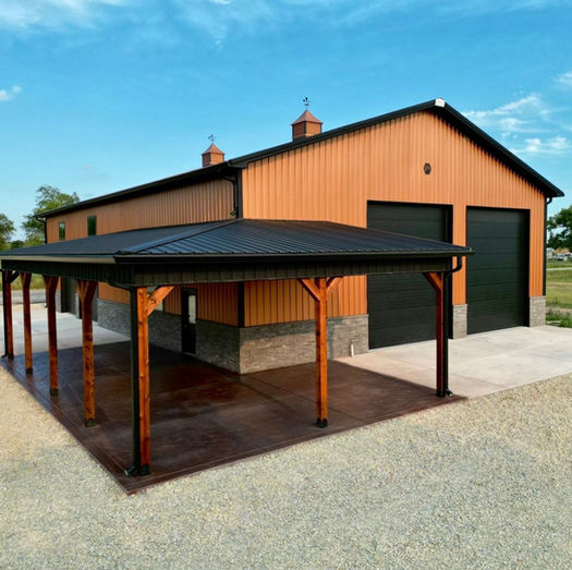 Brown custom barndominium with black metal roof and covered porch