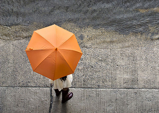 lady standing in the rain with orange umbrella