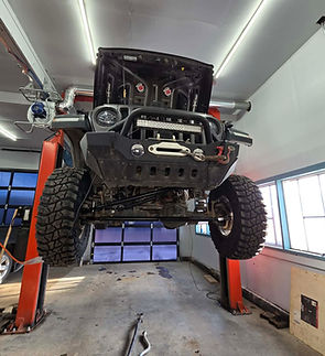 A vehicle hoisted in the air with new suspension parts installed.
