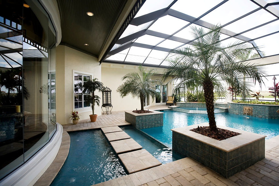 Indoor pool area with palm trees, stone path, and glass ceiling. Warm lighting reflects on the blue water, creating a serene ambiance.