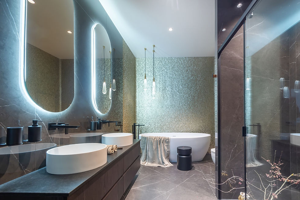 Modern bathroom with oval mirrors and glowing backlights, double sinks, a large bathtub, pendant lights, and dark marble surfaces.