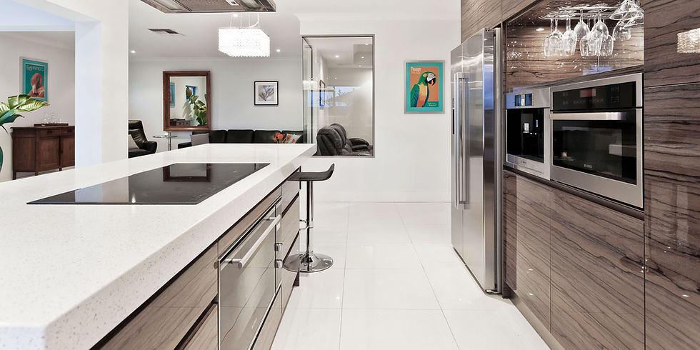 Modern kitchen with glossy wood and white surfaces, island cooktop, bar stool, stainless steel appliances, and vibrant artwork on walls.