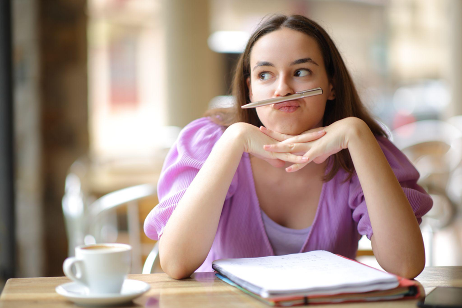 A young girl balances a pen on her upper lip, while looking to the side