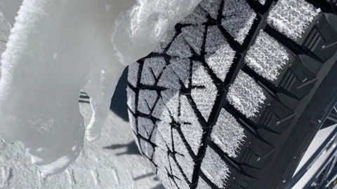 Close-up of Bridgestone Blizzak winter tire showing deep tread for ice and snow traction on 4x4 rental.