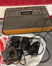 Vintage Atari video game console with accessories; brown and black design.