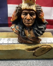 Native American Indian bust statue with eagle headdress and American flag background.