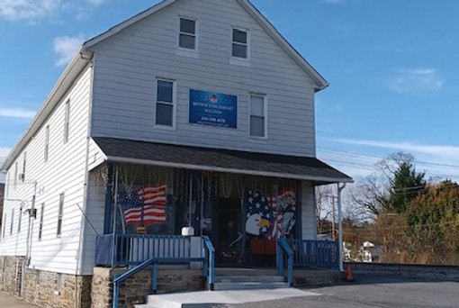 White building with a sign and blue awning. Thurmont Auction. HOME