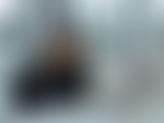 A person sits at a desk with a laptop, holding their head in frustration. Papers are scattered, and the office setting has large windows.