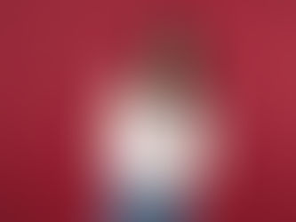 Woman in white shirt and jeans, smiling excitedly, holds fan of US dollar bills against red background, fist raised in celebration.