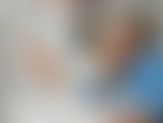 Smiling woman in blue sweater using laptop, book open, pencil cup nearby. Background shows a calendar with November. Cozy home office vibe.