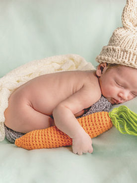 Newborn baby sleeping soundly on their belly, captured in a candid and heartwarming photograph.