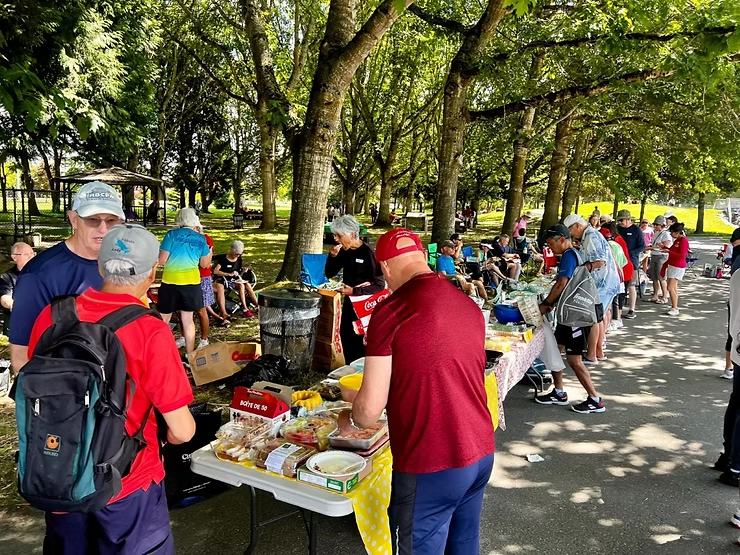A group of people at a pickleball court taking food from a buffet table.