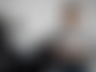 Man in a gray "Colonial Engineering Inc." shirt holds a ring under studio lights. Camera crew filming, text "CREW" on shirt. Focused mood.