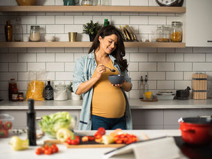 Mulher grávida preparando uma refeição vegetariana na cozinha