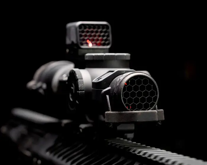 One Hundred Concepts ScopeCap Pro™ Ruggedized in black color attached to a LPVO on an AR15 rifle, with ScopeCap lens off