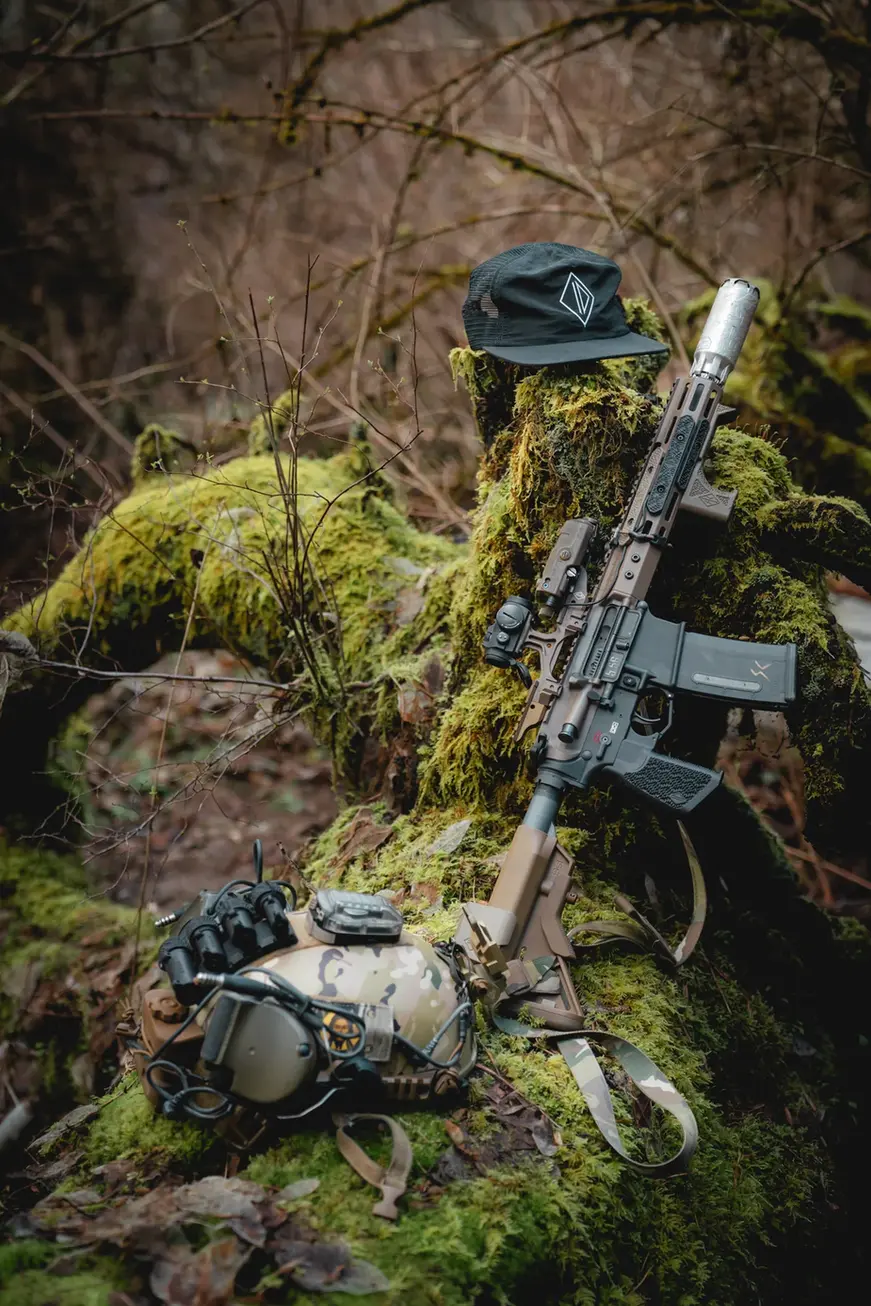 SC Irregulars ID Mesh Back Pack Hat next to an AR15 in a forest setting