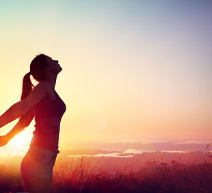 a women standing and spreading arms during sunset