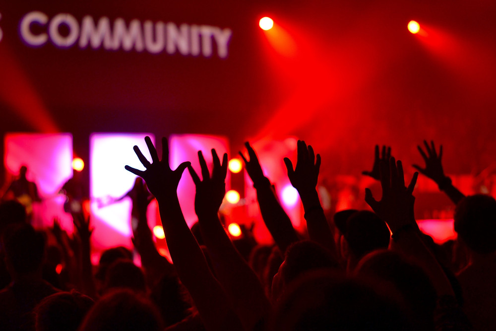 crowd with hands raised as they worship together in community