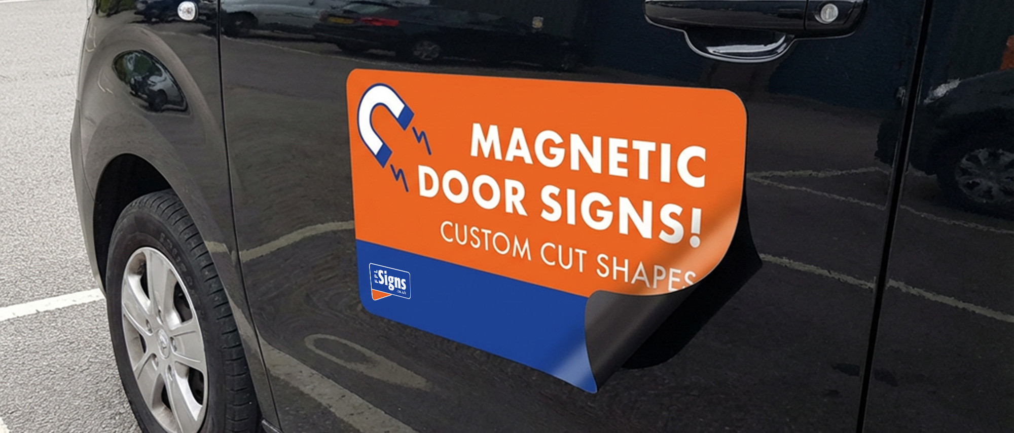 A magnetic sign on the side of a black van, the corner is peeling up