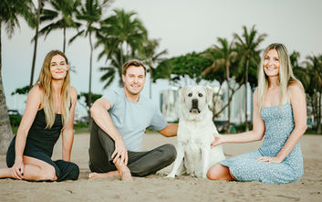 A family and their dog pose on the beach in Waikiki, Hawaii