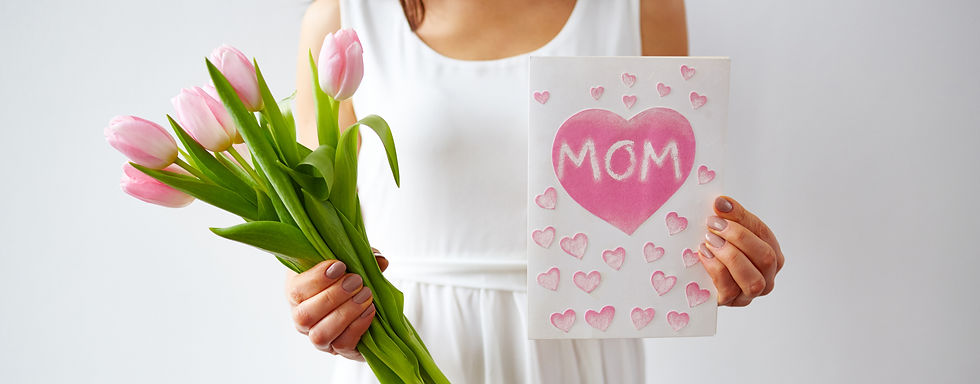 Woman holding flowers and a card with "Mom" on it