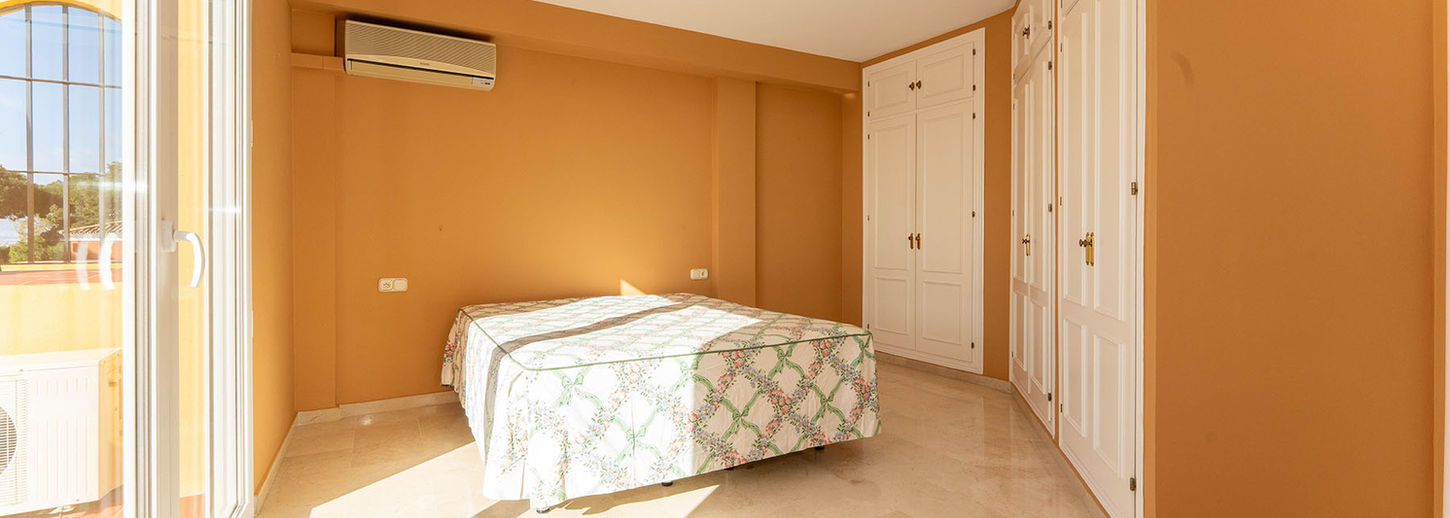 Vista amplia del dormitorio principal con armarios empotrados blancos de pared a pared en chalet en venta en El Morlaco.