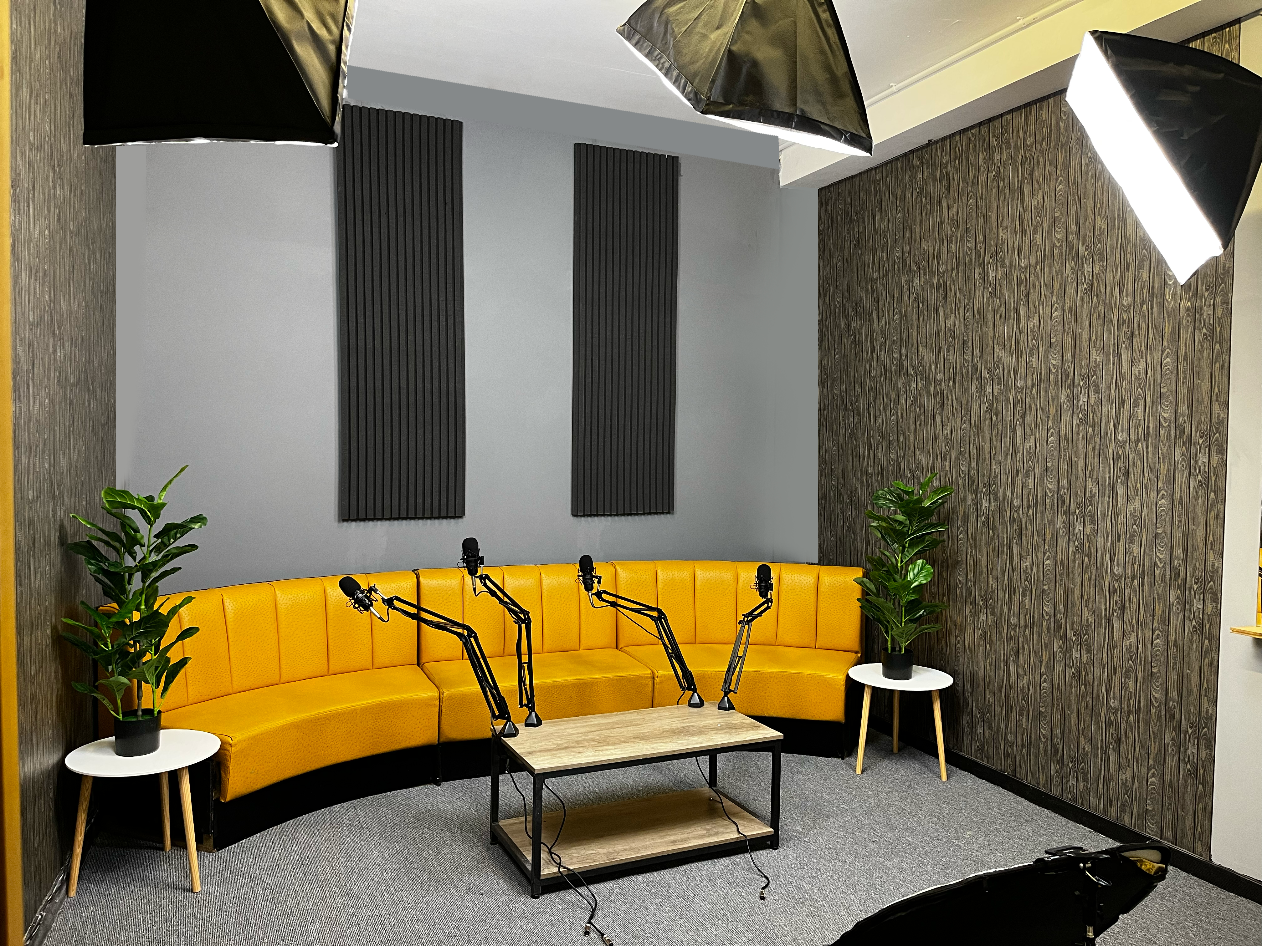 Fusion Creative Studios' dressed yellow-sofa podcast set with microphones, softbox lights and acoustic panels.