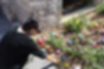 Woman placing colorful painted rocks in a garden.