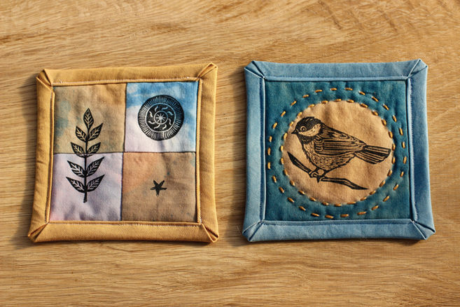 Hand sewn fabric coasters made with naturally dyed fabrics and printed with block prints of a chickadee, leaf, star, and circle design