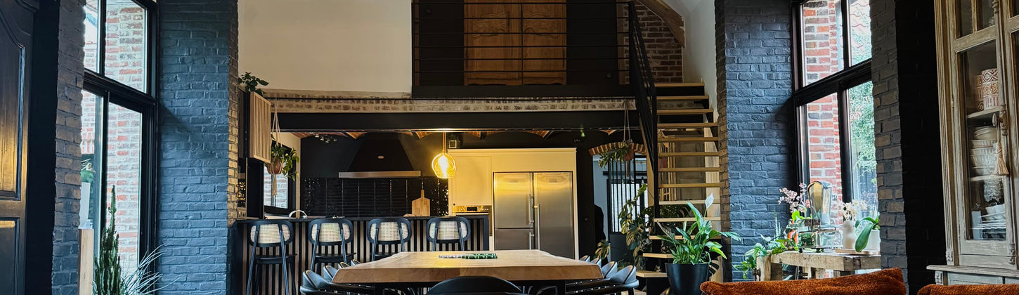 Salle à manger rénovée, ambiance chaleureuse avec table et chaises en bois, tons noirs et bois.