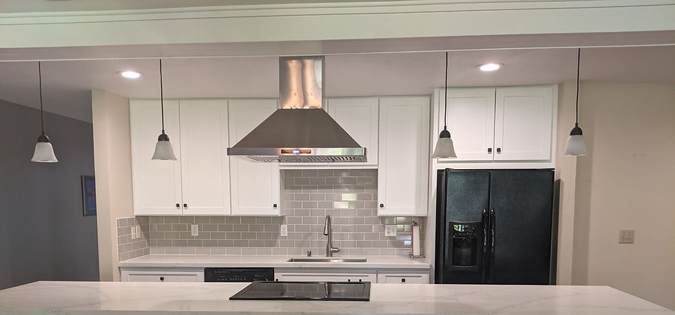 Front view of kitchen with cream quartz countertop and grey tile backsplash with white cabinets