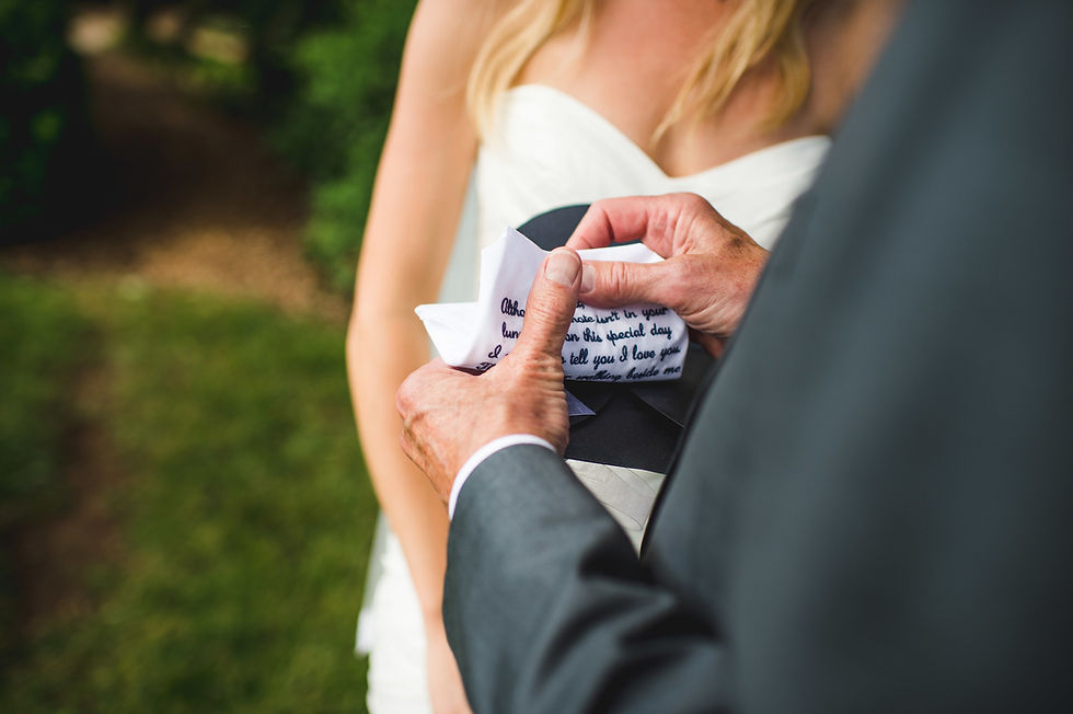 Close-up of hands holding a small handwritten note beside a person in a white dress