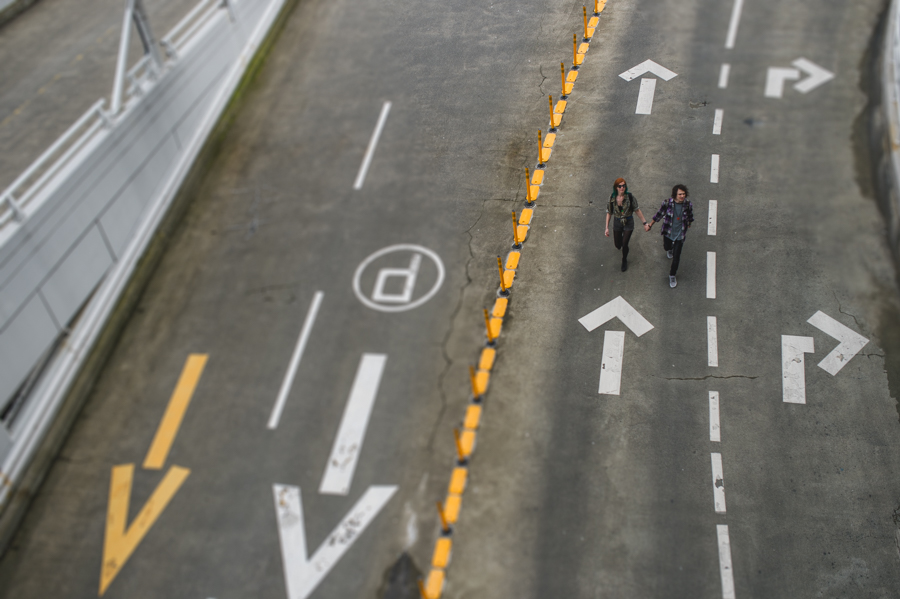 Overhead view of two people on a paved lane marked with arrows and dashed lines.