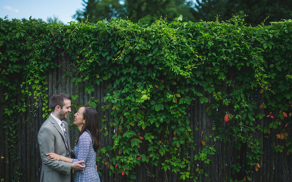 Couple embracing in front of an ivy-covered fence