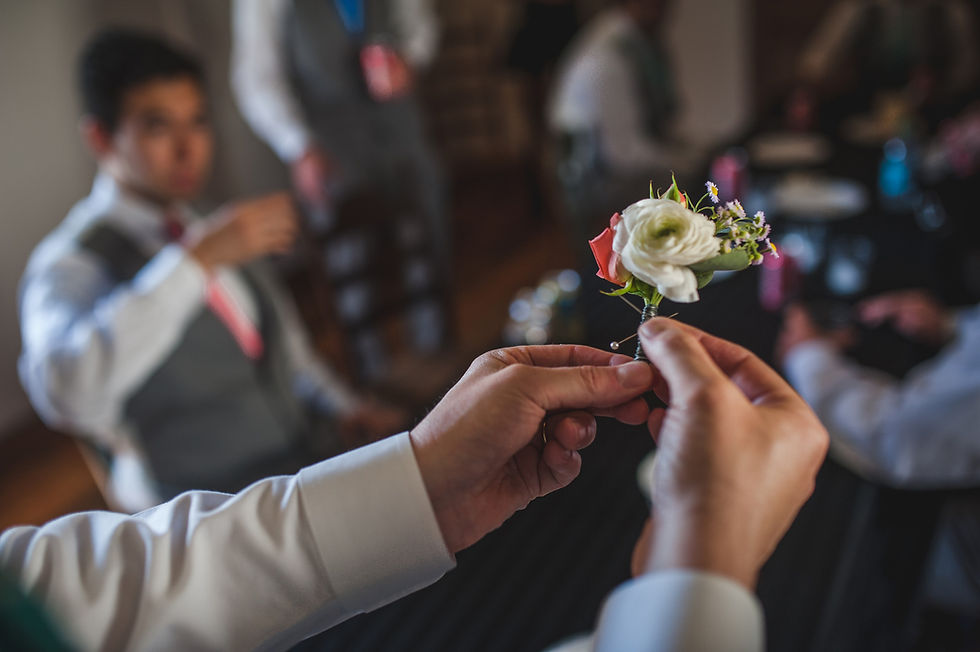 Hands meet in close-up, with wedding guests soft in the background.