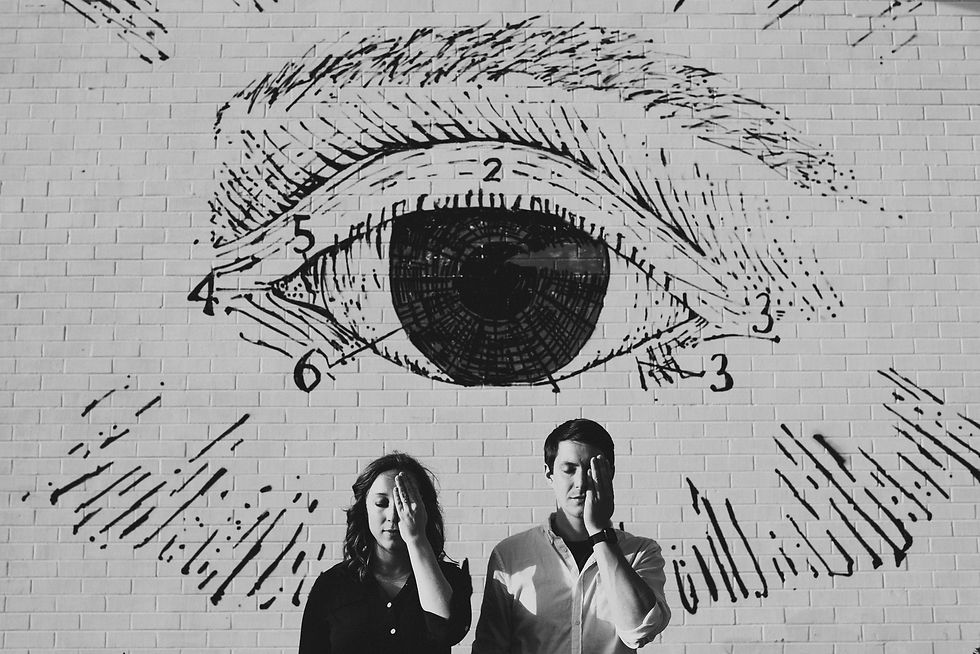 Couple posing beneath a large eye mural.