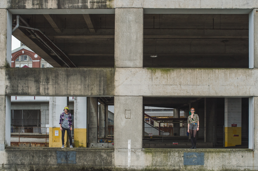 Two people standing apart beneath a concrete structure with large rectangular openings.