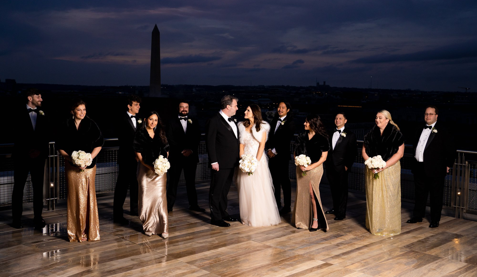 Wedding party on the International Spy Museum rooftop at dusk, with the Washington Monument behind them.