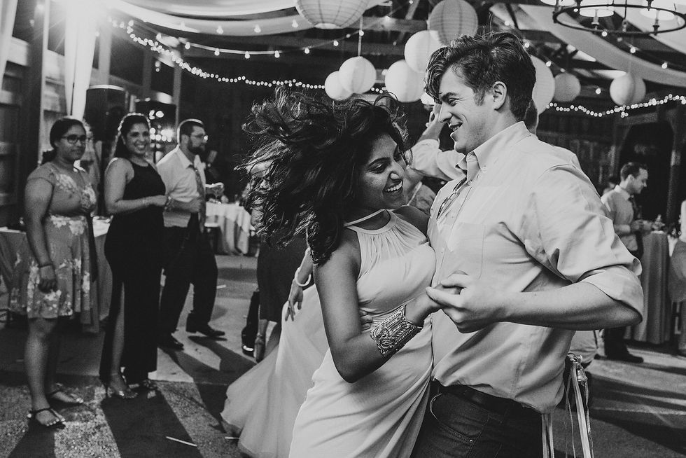 Bride and groom dancing beneath lanterns and string lights