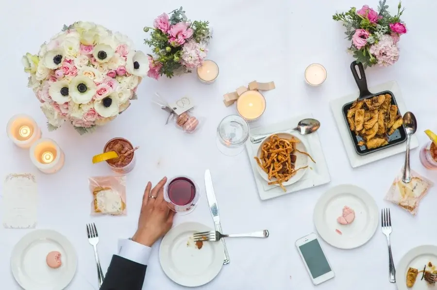 Overhead view of a reception table with flowers, plates and glassware.