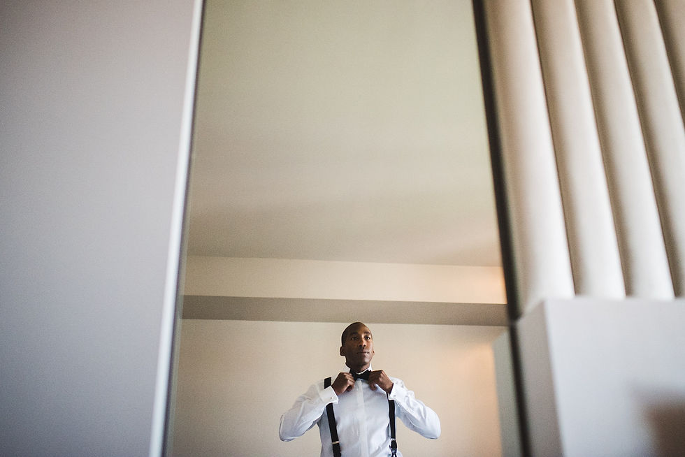 Nigel adjusting his bow tie in a mirror before the wedding