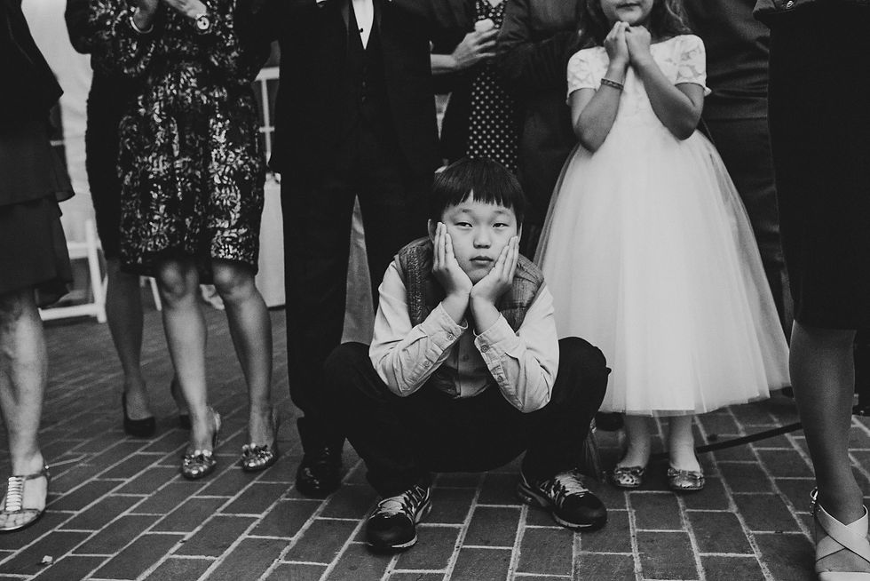 Black-and-white photograph of a boy crouching with his face in his hands beside a girl in a white dress