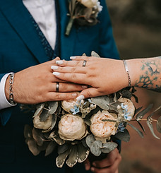 Brautstrauß mit den Händen des Brautpaares, inklusive Ringe