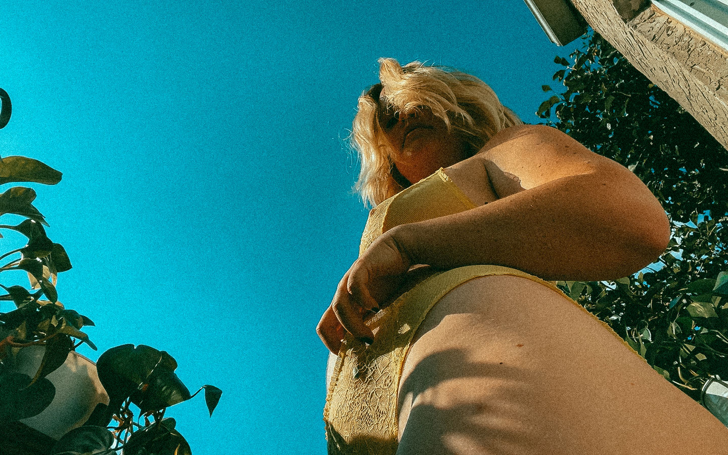 woman wearing mustard yellow lingerie looks down at camera