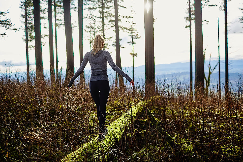 beautiful young girl walking in forest in running clothes standing on log.jpg